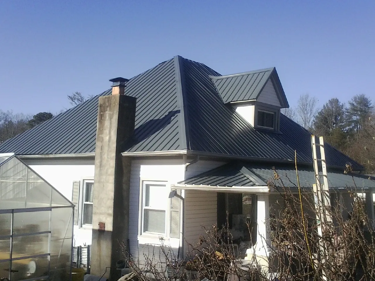 Dark blue standing seam metal roof on a white farmhouse with dormer — Slate & Tile Roof Repair by Roofing Brothers in Easthampton