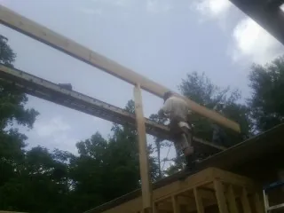 Carpenter setting a ridge beam over a new addition frame — Ice Dam Removal by Roofing Brothers in Easthampton