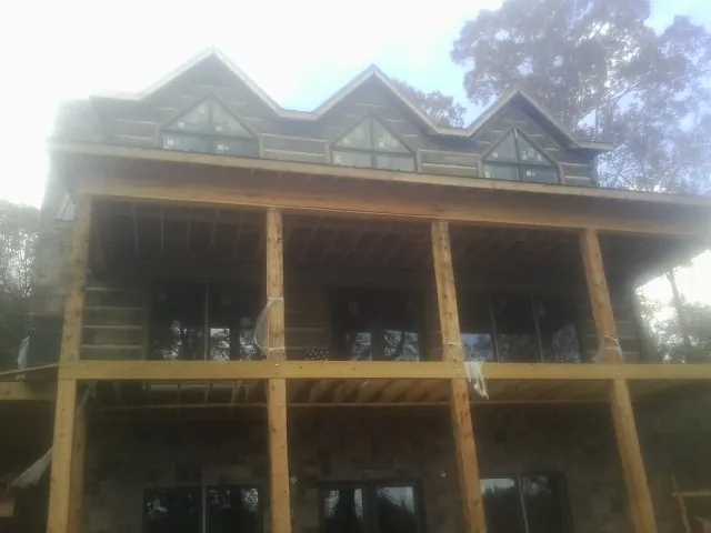 Dormers and porch framing on a large log home under construction — Roof Coating work by our crew in Easthampton