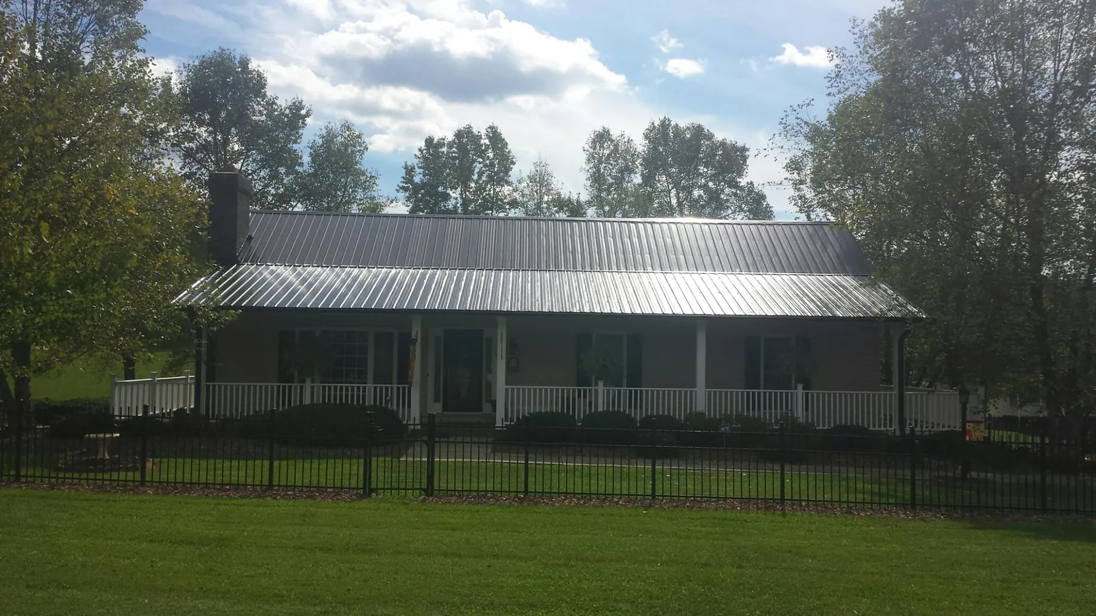 Gray metal roof on a brick ranch with a full width front porch — Gutter Guard Installation work by our crew in Easthampton