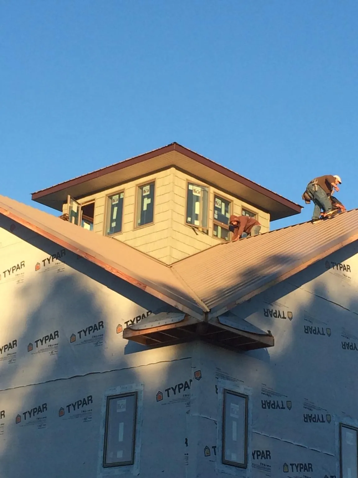 Roofers working around a rooftop cupola on a new metal roof at sunset — Roof Waterproofing in Easthampton by Roofing Brothers
